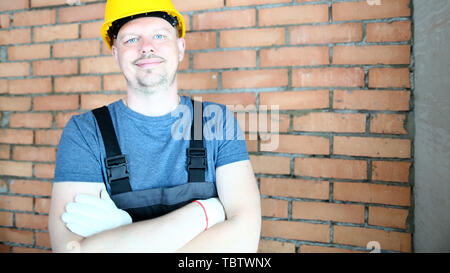 Portrait of laughing male looking at camera joyfully. Self-confident builder posing in protective hardhat prevent any trauma and injury. Constructor s Stock Photo