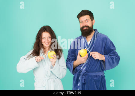 Keep teeth healthy. Healthy habits. Brush teeth every morning. Oral hygiene. Couple bathrobes hold toothbrushes and apples. Personal hygiene. Couple in love cleaning teeth. Freshness and cleanliness. Stock Photo