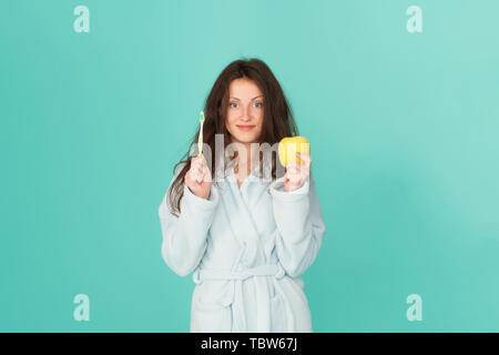 Oral hygiene. Woman bathrobe hold toothbrush and apple. Personal hygiene. Girl cleaning teeth. Freshness and cleanliness. Keep teeth healthy. Healthy habits. Brush teeth every morning. Dental care. Stock Photo