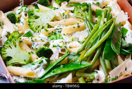 Pasta with green vegetables and creamy sauce in black bowl on grey stone background. Close up. Stock Photo