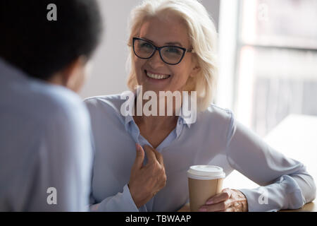 Excited mature businesswoman talking with colleague during coffee break Stock Photo