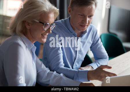 Young businessman and mature woman working on computer project together Stock Photo