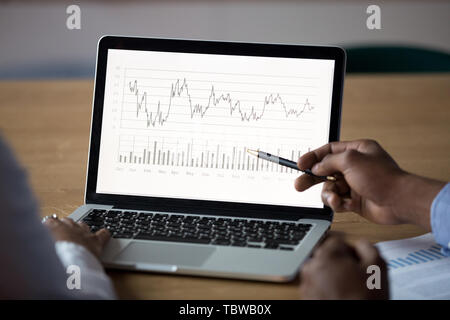 Close up African American businessman analyzing graphs on laptop screen Stock Photo