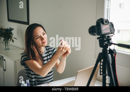 Girl videoblogger or beauty blogger records video for subscribers. She shows lipstick and tells how to use it properly. Stock Photo