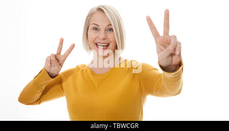 happy excited middle aged woman showing the sign of victory Stock Photo