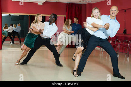 Young smiling people practicing passionate samba in dance class Stock Photo