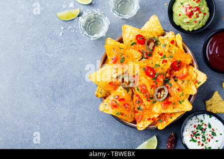 Nachos chips with melted cheese and dips variety. Top view. Copy space. Stock Photo