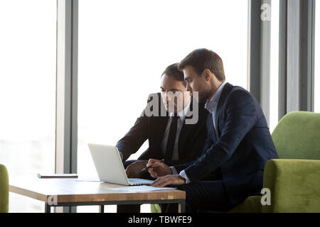 Focused business partners negotiate working on laptop Stock Photo