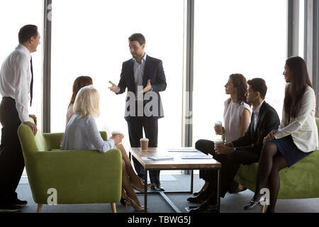 Businesspeople enjoy coffee talking during informal office meeting Stock Photo