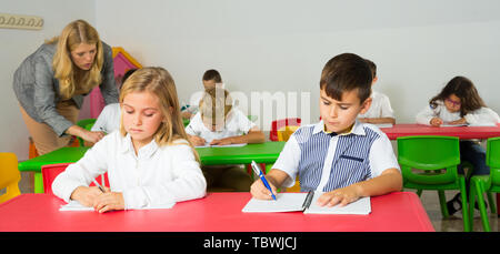 Female teacher helping schoolchildren doing their task in classroom Stock Photo
