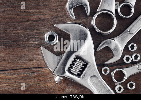 Bolts, nuts, wrenches and spanners on wooden table background with copy space. Top down macro view. Stock Photo