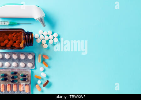 Pharmaceutical medical pills and capsules in packs, an injector syringe, ear thermometer and tablets spilled from a drug bottle Stock Photo