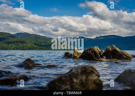 mountains, many rocks, cloudy sky, lake water Stock Photo
