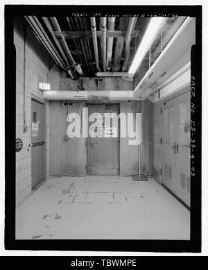 MTR WING, TRA604, INTERIOR. BASEMENT. INTERIOR VIEW FROM SAME LOCATION IN WEST CORRIDOR AS PHOTO ID33G42 BUT CAMERA FACES SOUTH. SIGN ON DOOR FOR PIPE TUNNEL WARNS OF RADIOLOGICAL AND ASBESTOS HAZARDS. DOOR HAS METAL HASPS. SIGN ON OVERHEAD WASTE HEAT RECOVERY PIPES SAYS THEY CONTAIN ASBESTOS FREE INSULATION. FIRE DOOR AT LEFT LEADS TO STAIRWAY TO FIRST FLOOR. DOOR AT RIGHT LEADS TO ROOM WHICH ONCE CONTAINED MTR LIBRARY. INL NEGATIVE NO. HD46134.  Mike Crane, Photographer, 22005  Idaho National Engineering Laboratory, Test Reactor Area, Materials and Engineering Test Reactors, Scoville, Butte  Stock Photo