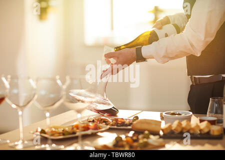 Mid section portrait of professional sommelier pouring wine while preparing for wine tasting session in sunlight, copy space Stock Photo