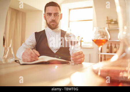 Portrait of professional sommelier looking away pensively during wine tasting session in winery lit by sunlight, copy space Stock Photo