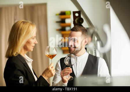 Warm toned portrait of two professional sommeliers smiling cheerfully while examining wine during tasting session, copy space Stock Photo