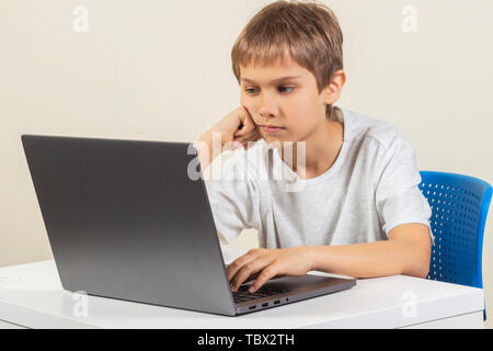 Boy sitting at the table and using laptop computer Stock Photo