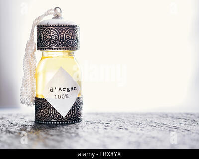 Decorative bottle with iron embossed in traditional Moroccan style with precious Moroccan argan oil on a rough stone surface Stock Photo