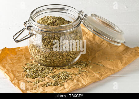 Dried fennel seeds in glass storage jar on white wooden table background Stock Photo