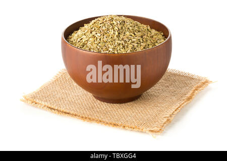 Dried fennel seeds in wooden bowl on burlap sack over white background Stock Photo