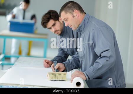 instructor showing apprentices how to paint Stock Photo