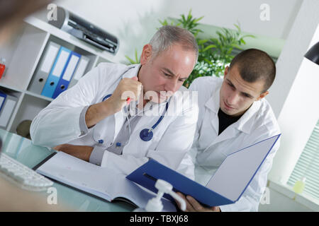 apprentice and doctor checking a patients folder Stock Photo