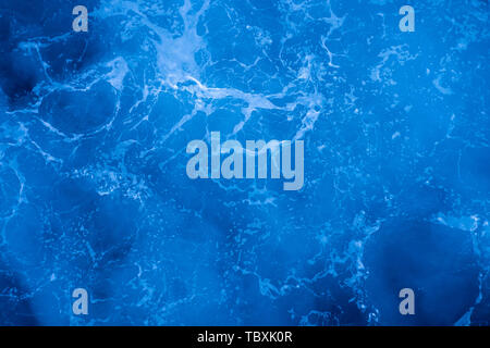 Dark blue deep sea surface, rippled water with sea foam and sparkling light Stock Photo