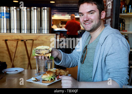 A man holding a Jucy Lucy aka Juicy Lucy cheeseburger, a Minnesota specialty in a Duluth restaurant.Duluth.Minnesota.USA Stock Photo
