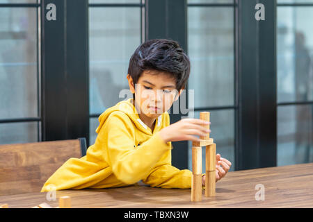 Little Boy is building wooden toy block tower Stock Photo