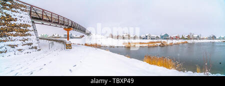 Panorama of a silvery lake with distant houses against cloudy sky in winter Stock Photo