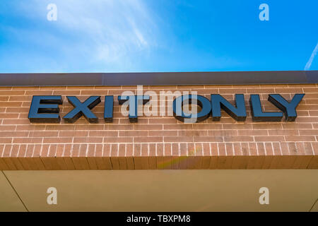 Close up of Exit Only sign on the exterior red brick wall of a building Stock Photo