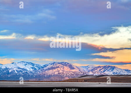 Panorama of a magnificent snow covered mountain beyond a lake at sunset Stock Photo