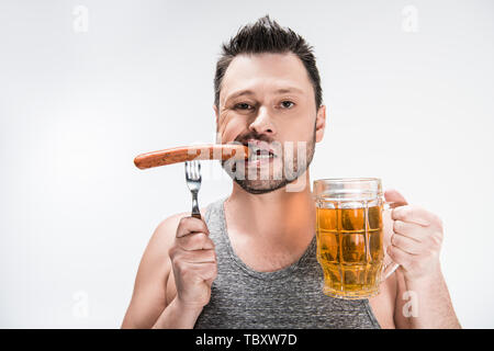 chubby man biting sausage and holding glass of beer isolated on white Stock Photo