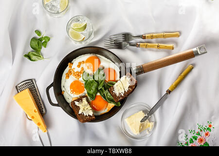 Frying pan with fried eggs on a light background. white tablecloth, flat lay. Stock Photo