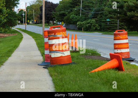 several orange barrels and traffic cones protecting a road repair Stock Photo