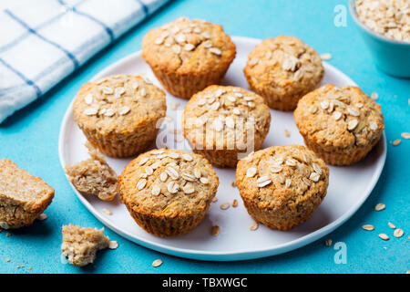 Healthy vegan oat muffins, apple and banana cakes with on a white plate. Blue background. Stock Photo