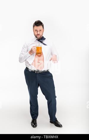 overweight man in tight shirt looking at camera while holding glass of beer and gesturing on white Stock Photo