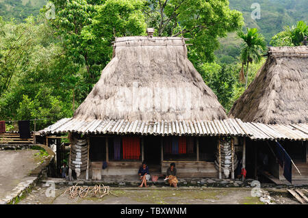 BENA, BAJAWA, INDONESIA - 23 APRIL 2011: Ethnic women sitting on the doorstep traditional grass hut in the Bena minority village on the Flores island  Stock Photo