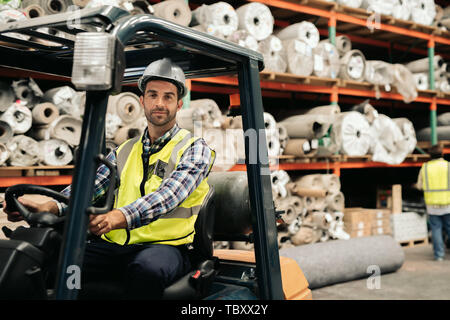 Smiling worker using a forklift to move warehouse stock Stock Photo