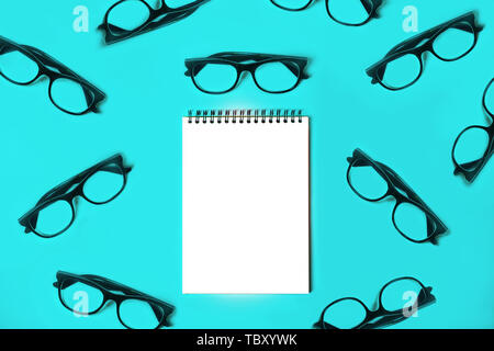 Notepad with trendy glasses on blue background. Stock Photo
