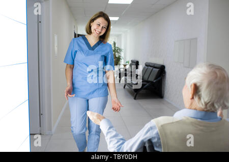 nurse smiling to senior man in wheelchair at nursing home Stock Photo