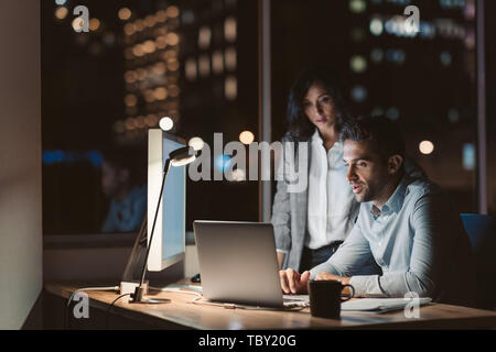 Two focused colleagues working in an office late at night Stock Photo