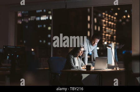 Young business colleagues working overtime together at an office desk Stock Photo