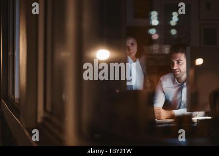 Colleagues working together inside of an office late at night Stock Photo