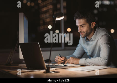 Young businessman writing down notes while working at night Stock Photo
