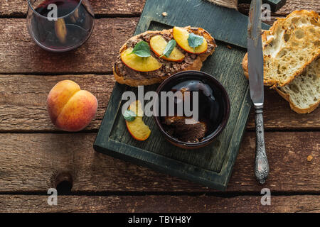 Chicken liver pate with griiled bread and peach, rustic style. Stock Photo