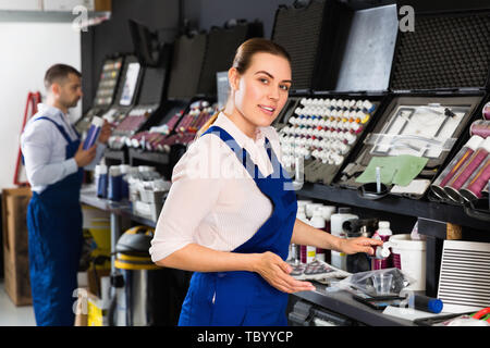 Cheerful positive  female car painter preparing paints for paintwork in modern auto repair shop Stock Photo