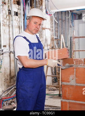 Professional builder mason installing red brick inside building in process of construction Stock Photo