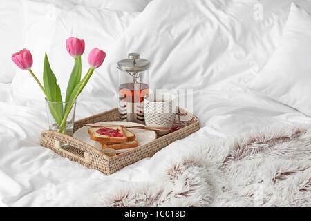 Tray with tasty breakfast on bed Stock Photo